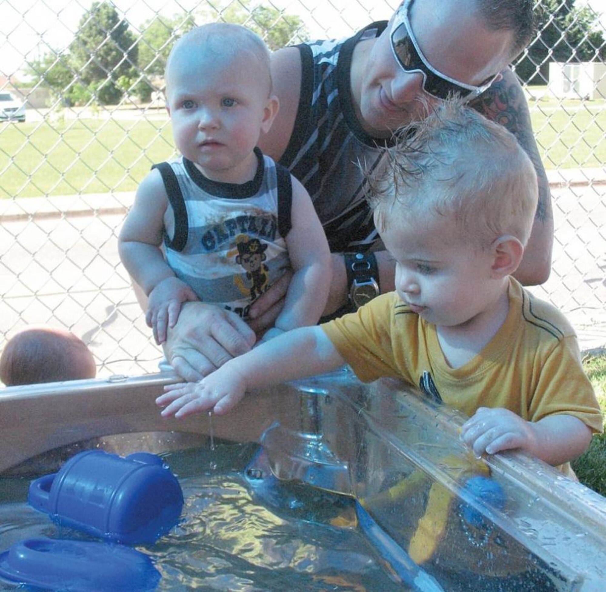 Daniel Nichiporuk holds his son Skylar as Bishop Ketron reaches into a water sensory table for a floating toy. Each class at the Hill Air Force Base, Utah, Child Develpment Center planned activities appropriate for their kids' age level and then supervised them closely. (Courtesy photo by Mary Lou Gorny)