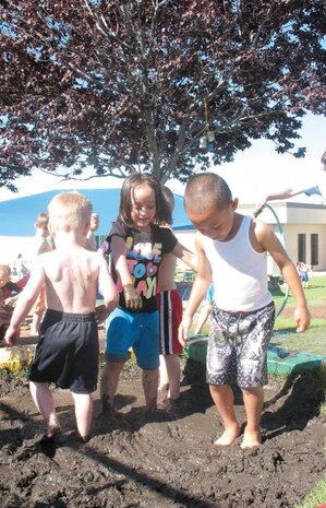 Akoni Suafoa (right) and Riley Miranda stand in a mud pit created just for International Mud Day at the Hill Air Force Base, Utah, Child Development Center  playground. The day was first started in Nepal when staff members organized a day just so orphans kept indoors most of the time would be allowed to experience nature and learn about their environment by playing in the mud. (Courtesy photo by Mary Lou Gorny)