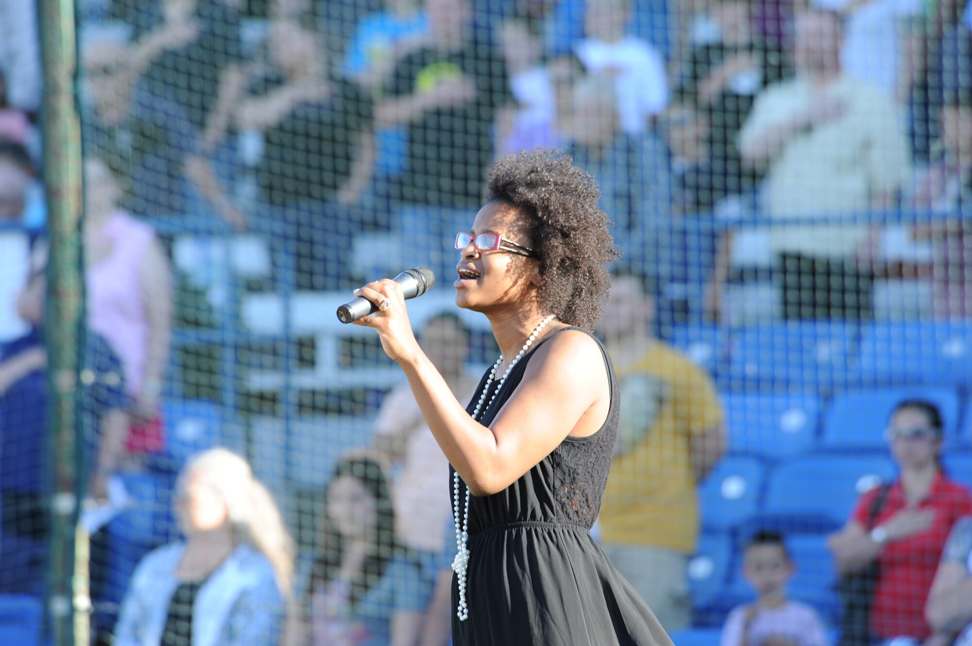 Senior Airman Christina Arrington-Silva, 341st Medical Support Squadron medical technician, sings the national anthem at the start of the baseball game as the audience places their hands over their hearts at Centene Stadium in Great Falls, Mont. June 29. (U.S. Air Force photo/Senior Airman Katrina Heikkinen)