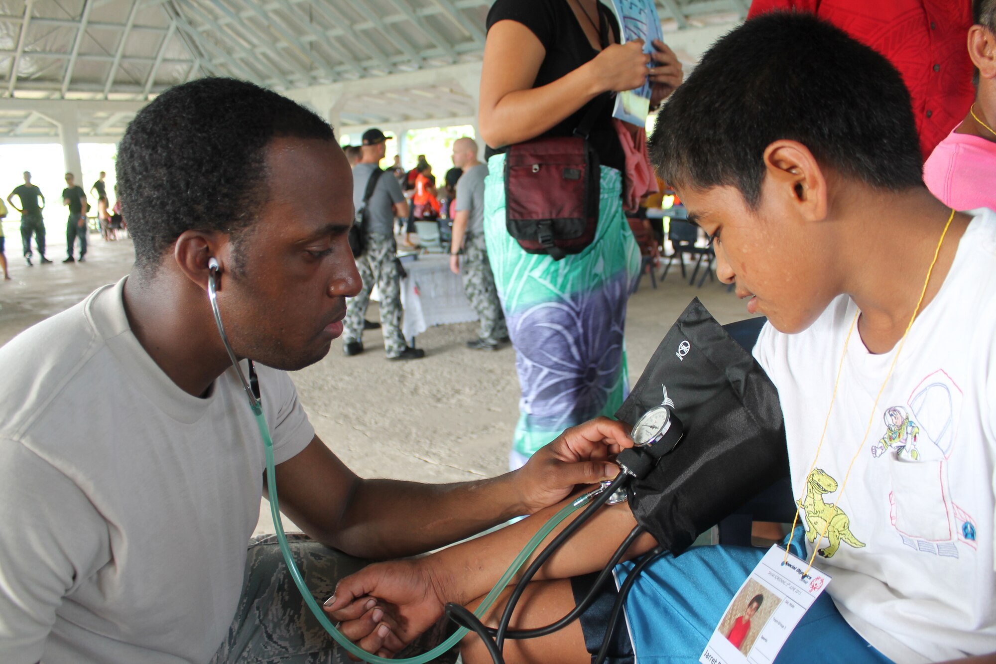 Senior Airman Rainier Jeffrey, 15th Medical Group, checks a young patient's blood pressure and pulse during a recent stop for humanitarian operation Pacific Partnership 13. As a medical technician deployed with the Navy in support of the humanitarian aid mission, it is Jeffrey’s job to share medical knowledge with the auxiliary nurses at the village hospitals in Australia, New Zealand, Japan and Canada, as well as provide medical assistance to the villagers. (Courtesy photo)