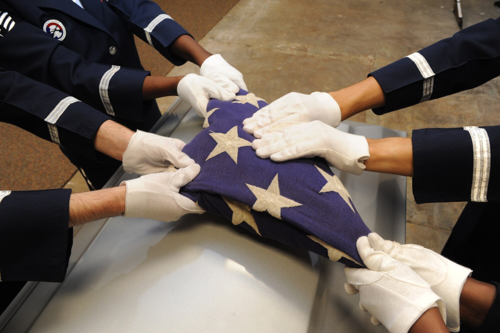 Following a flag-folding ceremony over a casket, members of the Keesler Honor Guard prepare the flag for presentation to a family member of the deceased during a training session June 26, 2013, at the Locker House, Keesler Air Force Base, Miss. The Keesler Honor Guard’s primary mission is to render military honors for our nation’s fallen service members.  They also support other ceremonial functions such as saber/sword cordons, parades, posting of the colors at retirements, change of commands, prisoner of war/missing in action honors, weddings, sporting events and venues within the local community.  (U.S. Air Force photo by Kemberly Groue)