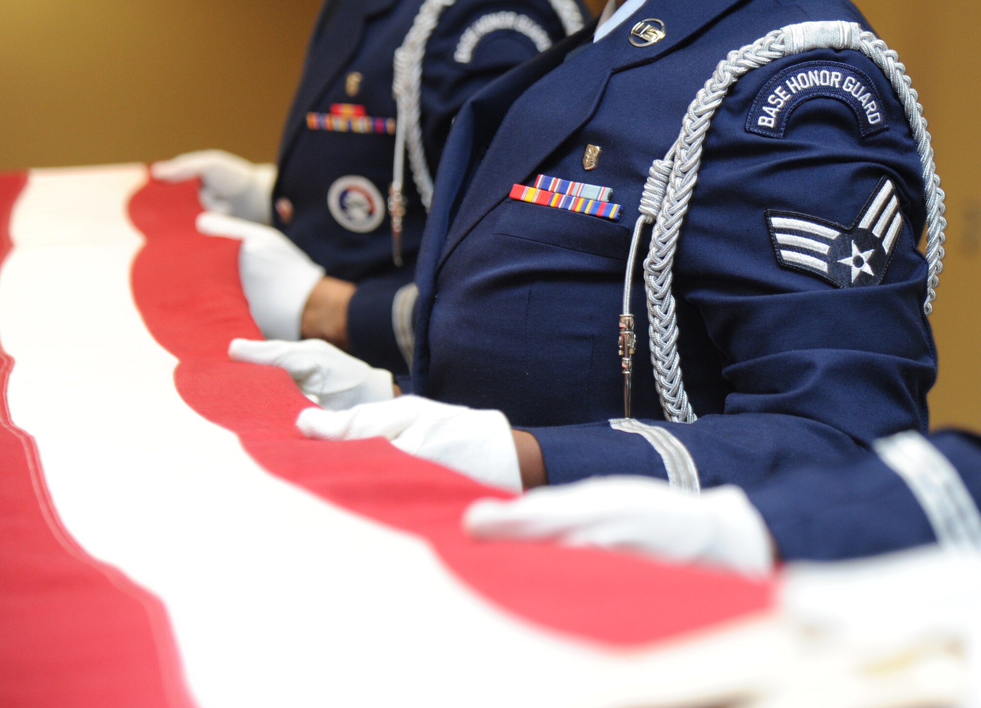Keesler Honor Guard members conduct a flag-folding ceremony over a casket during a training session June 26, 2013, at the Locker House, Keesler Air Force Base, Miss. The Keesler Honor Guard’s primary mission is to render military honors for our nation’s fallen service members.  They also support other ceremonial functions such as saber/sword cordons, parades, posting of the colors at retirements, change of commands, prisoner of war/missing in action honors, weddings, sporting events and venues within the local community.  (U.S. Air Force photo by Kemberly Groue)
