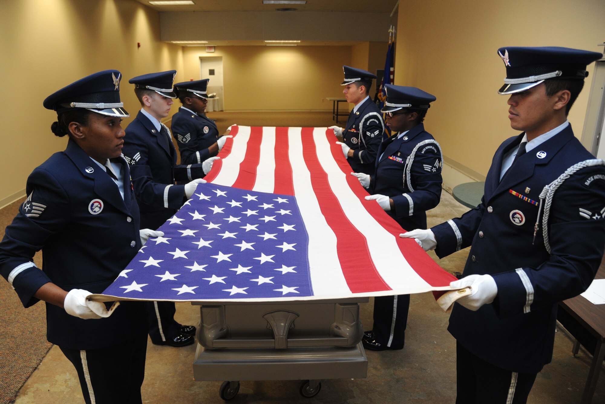 Staff Sgt. Kayciann Gordon, Senior Airman Quinton Moll, Staff Sgt. Giovanna Gladney, Airman 1st Class Pedro Ayala, Senior Airman Laquita Moore and Airman 1st Class Abraham DeLuna, Keesler Honor Guard members, prepare to conduct a flag-folding ceremony over a casket during a training session June 26, 2013, at the Locker House, Keesler Air Force Base, Miss. The Keesler Honor Guard’s primary mission is to render military honors for our nation’s fallen service members.  They also support other ceremonial functions such as saber/sword cordons, parades, posting of the colors at retirements, change of commands, prisoner of war/missing in action honors, weddings, sporting events and venues within the local community.  (U.S. Air Force photo by Kemberly Groue)