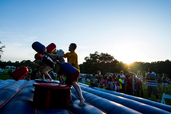 A volunteer assists a child in battling his father in a pugil stick match June 28, during the 2013 Freedom Fest at Marrington Plantation at Joint Base Charleston – Weapons Station, S.C. Nearly 1,500 Airmen, Sailors, civilians and their families attended the celebration which included food, drinks, festival rides, music and fireworks. (U.S. Air Force photo/ Senior Airman George Goslin)