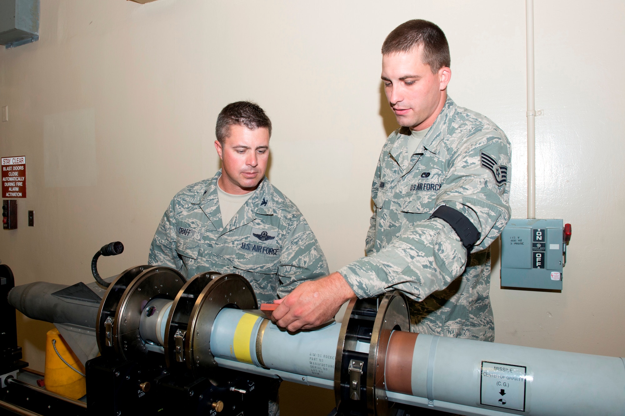 Staff Sgt. Kyle Larson, 325th Maintenance Squadron precision guided munitions crew chief, shows Colonel David E. Graff, 325th Fighter Wing commander, how to inspect the contact buttons on the rocket motor and identify excessive wear and corrosion during the Airman Shadow program June 27. (U.S. Air Force photo by Lisa Norman)