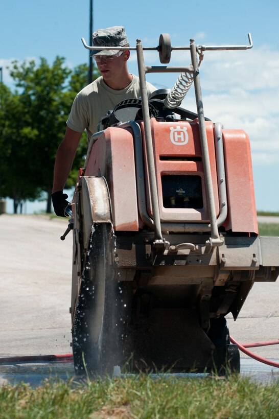 Airman 1st Class James Holley, 28th Civil Engineer Squadron heavy equipment and pavement technician, removes concrete during minor repairs in front of the 28th Bomb Wing Headquarters building on Ellsworth Air Force Base, S.D., June 27, 2013. The heavy equipment and pavement technicians are required to inspect every road and parking lot for structural integrity and damage after the winter season. (U.S. Air Force photo by Senior Airman Kate Maurer/Released) 