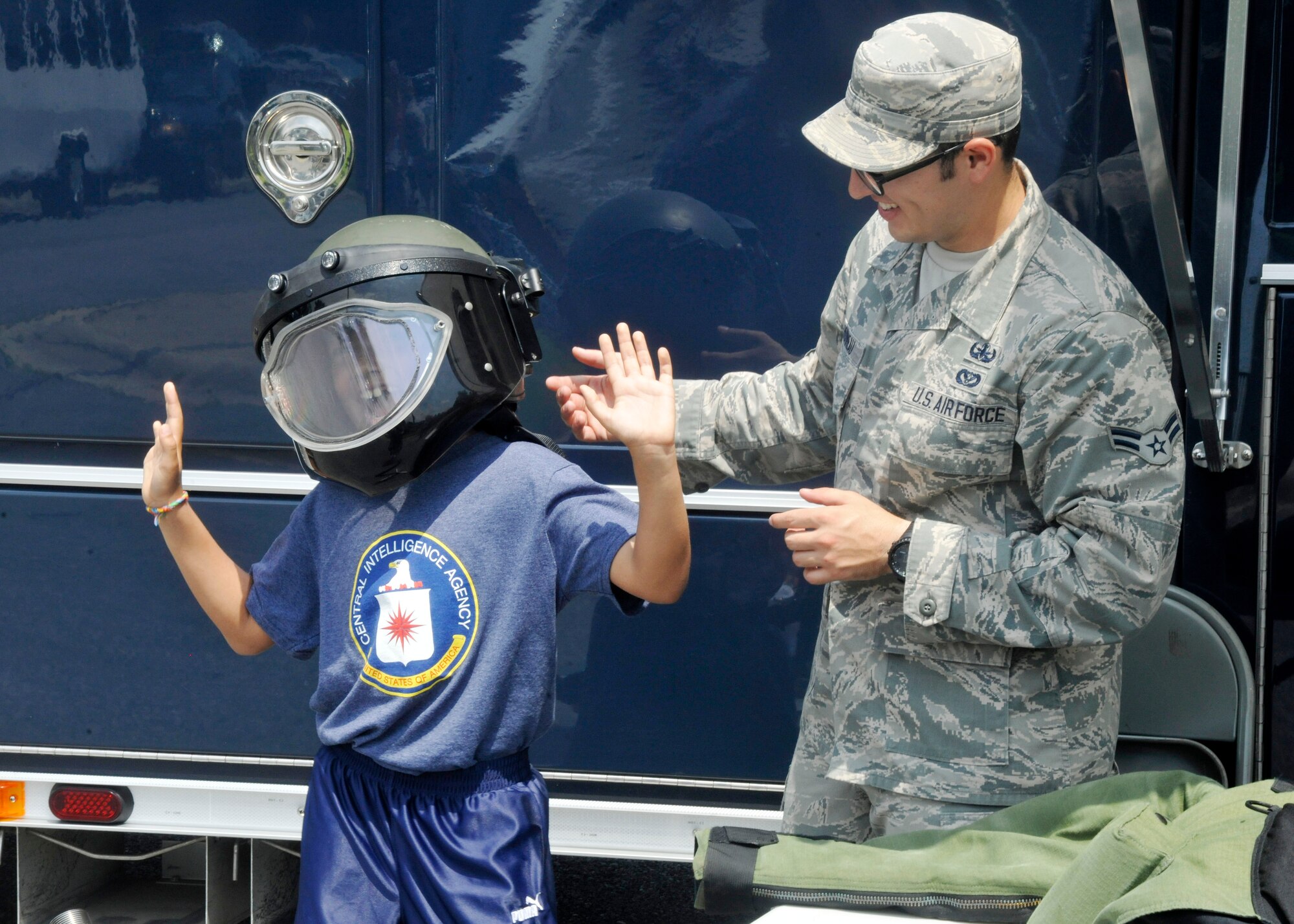 Airman 1st Class Christopher Bonneau, 11th Civil Engineer Squadron explosive ordnance disposal technician, helps a child try on a bomb suit helmet during Operation KID Mode, held June 28, 2013 at Joint Base Andrews, Md. Operation KID Mode is a kid-friendly, pretend deployment mobility line designed to help children of service members better understand their parents' actual deployment process. (U.S. Air Force photo/Senior Airman Lindsey A. Porter)