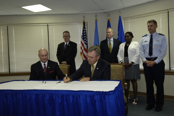 Midwest City Mayor Jack Fry signs the official Community Partnership Initiative Charter between Tinker and surrounding communities June 26. Also on hand are, from left, Oklahoma County Commissioner Ray Vaughn, Del City Mayor Brian Linley, Oklahoma City Mayor Mick Cornett, Oklahoma County Commissioner Willa Johnson and Col. Steven Bleymaier, former 72nd Air Base Wing and Tinker installation commander. (Air Force photo by Darren D. Heusel)