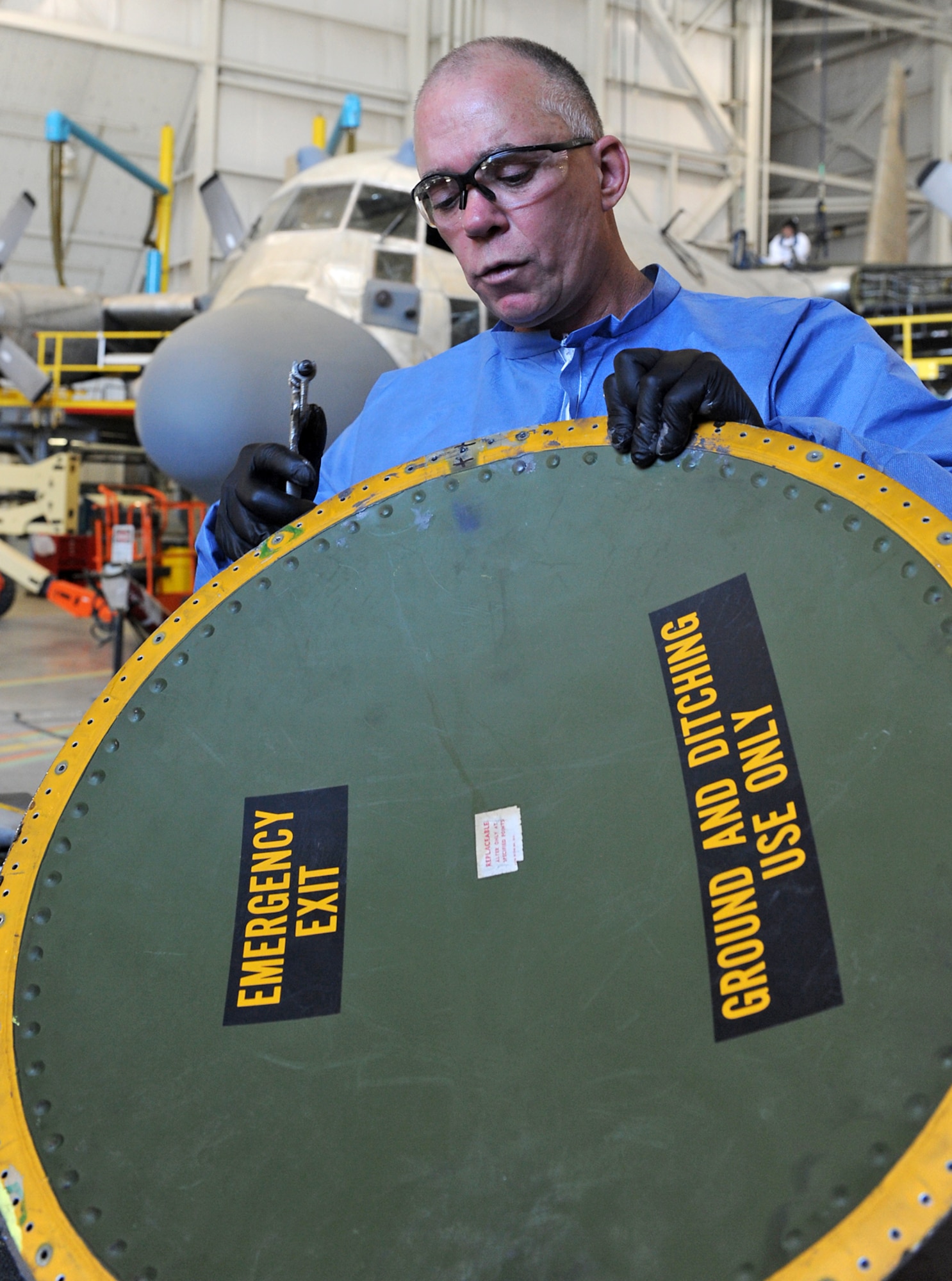 Philip Dixon, sheet metal mechanic, seals and rivets the ground and ditching escape hatch of a C-130 back together. Dixon and 42 other mechanics from Robins are working at Hill AFB, Utah supplying much needed manpower to the C-130 maintenance line to ensure the current repair schedule is kept on schedule. ( U. S. Air Force photo by Alex Lloyd/Released)