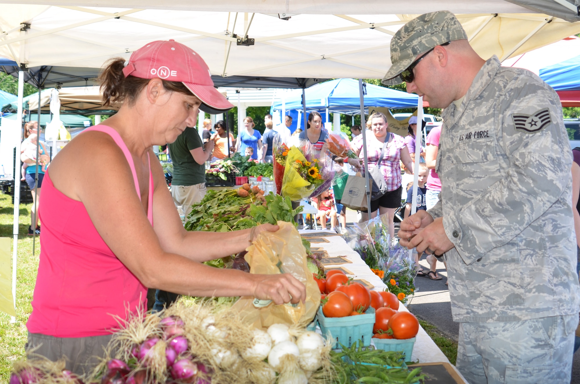 Staff Sgt. James McCarroll, 87th Communications Squadron airfield systems technician, purchases tomatoes from Lisa Durr at the “Homegrown for Heroes” farmer’s market June 20, 2013, at Patriot Park on Joint Base McGuire-Dix-Lakehurst, N.J. The vendors sold products to include organic fruits and vegetables, local honey, and homemade gifts. The farmer’s market is hosted by United Communities and will runs from June to September every Thursday from 10 a.m.-2 p.m.  (U.S. Air Force by Kim Wright/Released)