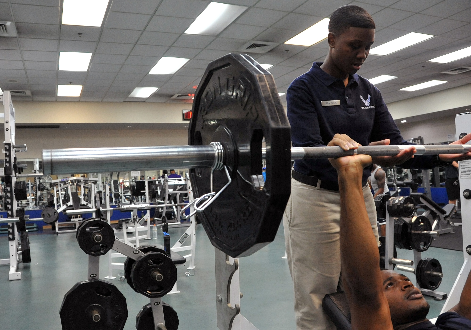Senior Airman Raashida Wise, 51st Force Support Squadron fitness specialist, assists Capt. Ilechukwu Agu, 731st Air Mobility Squadron air freight officer in charge, at the fitness center on Osan Air Base, Republic of Korea, June 28, 2013 Osan fitness specialists are trained to ensure members are using proper form on gym equipment.  (U.S. Air Force photo/Senior Airman Kristina Overton)