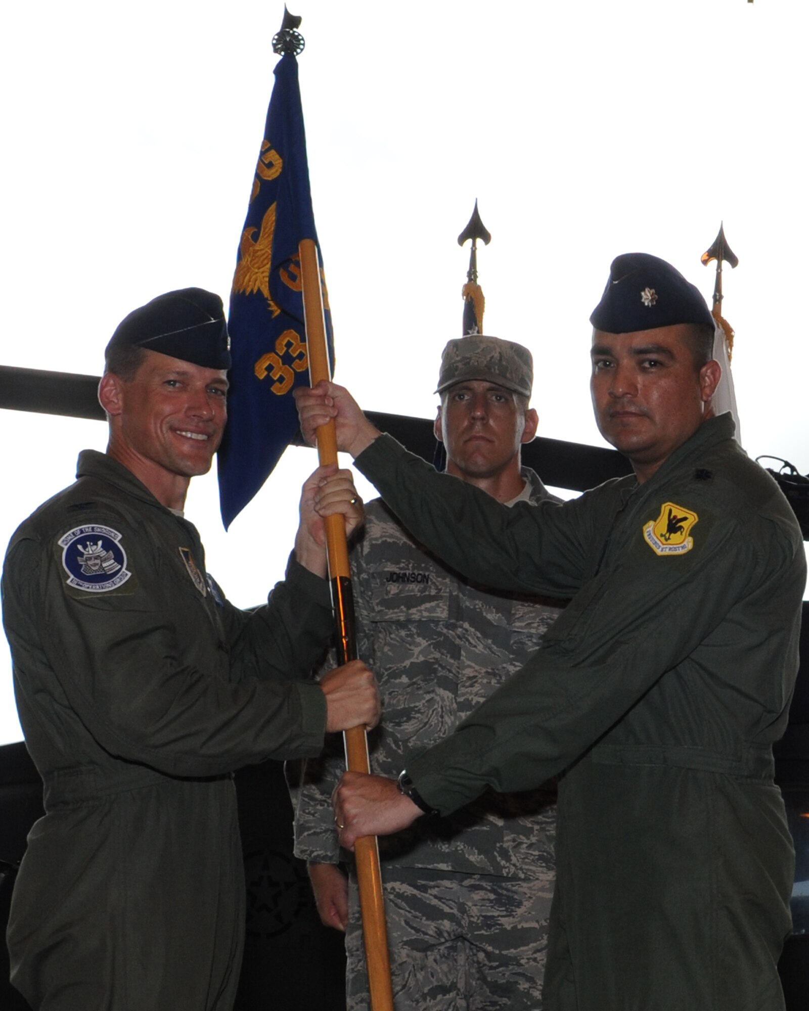 U.S. Air Force Col. Peter Milohnic, 18th Operations Group commander, passes the guidon to Lt. Col. Pedro Ortiz Jr., 33rd Rescue Squadron commander, during a change of command ceremony on Kadena Air Base, Japan, July 3, 2013.The 33rd RQS conducts day and night combat rescue operations over land or water in hostile and denied territories in support of the U.S. and its allies. They also maintain readiness for short mobilization, deployment and employment of the HH-60G Pavehawk helicopters and rescue forces supporting Pacific Command operations plans. (U.S. Air Force photo by Airman 1st Class Keith A. James/Released)