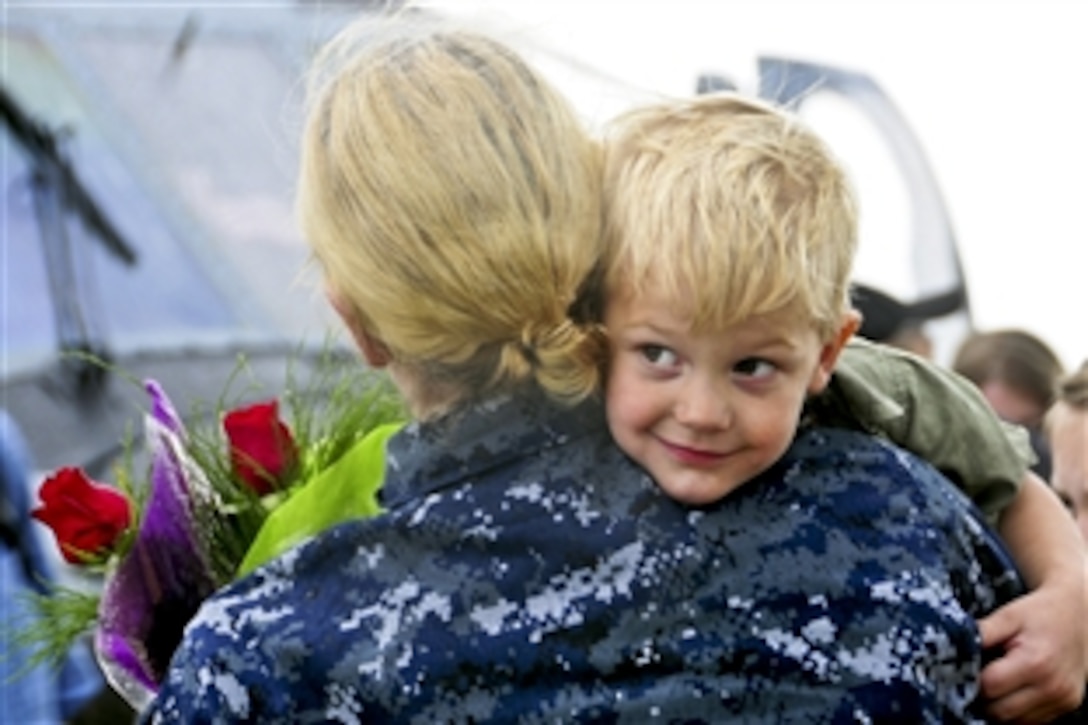 A sailor gets a homecoming hug from a boy during a celebration for the Dwight D. Eisenhower Carrier Strike Group at its homeport in Norfolk, Va., July 2, 2013. The carrier group is returning to its homeport after operating in areas of responsibility for the U.S. 5th and 6th fleets. The sailors are assigned to Helicopter Anti-submarine Squadron 5.