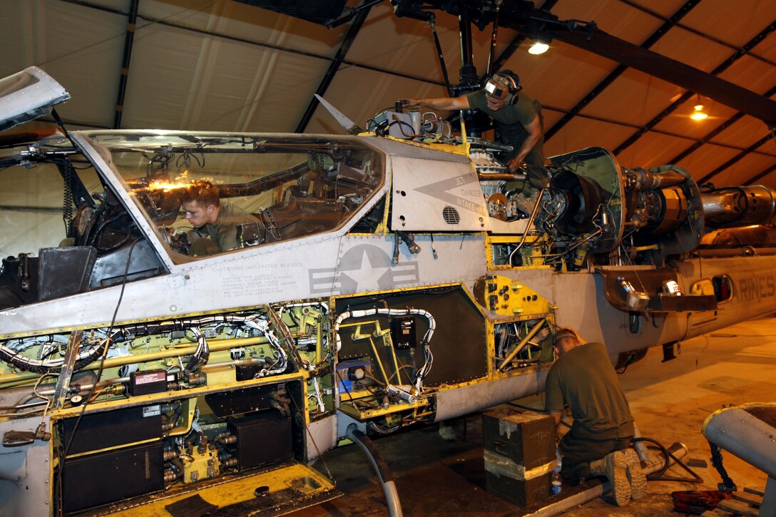 U.S. Marine Corps Lance Cpl. Jacob P. Hotchkiss, left, an avionics (AVI) technician, Cpl. Cody Michael Frances Posa, top right, a AVI technician, and Sgt. Joseph W. Massengale, an airframes mechanic, all with Marine Light Attack Helicopter Squadron 167 perform routine maintenance on a AH-1W Super Cobra helicopter at Camp Bastion, Helmand province, Afghanistan, June 24, 2013. The Marines performed maintenance on  the helicopter to meet inspection standards. (U.S. Marine Corps photo by Sgt. Gabriela Garcia/Released)