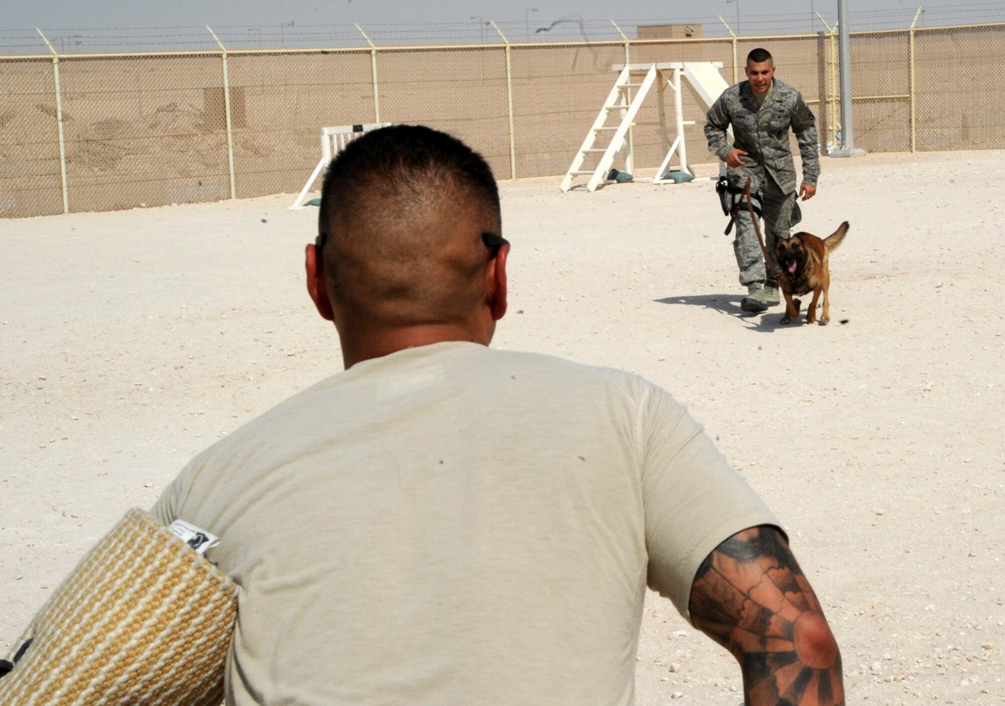 Senior Airman Andrew Hanus prepares to release Beni, onto Senior Airman Aaron Escalante during training at the 379th Air Expeditionary Wing in Southwest Asia, June 26, 2013. Hanus is a 379th Expeditionary Security Forces Squadron military working dog handler and Beni a 379th ESFS MWD both deployed from Travis Air Force Base, Calif. Escalante is a 379th ESFS MWD handler deployed from Davis-Monthan Air Force Base, Ariz. (U.S. Air Force photo/Senior Airman Bahja J. Jones) 