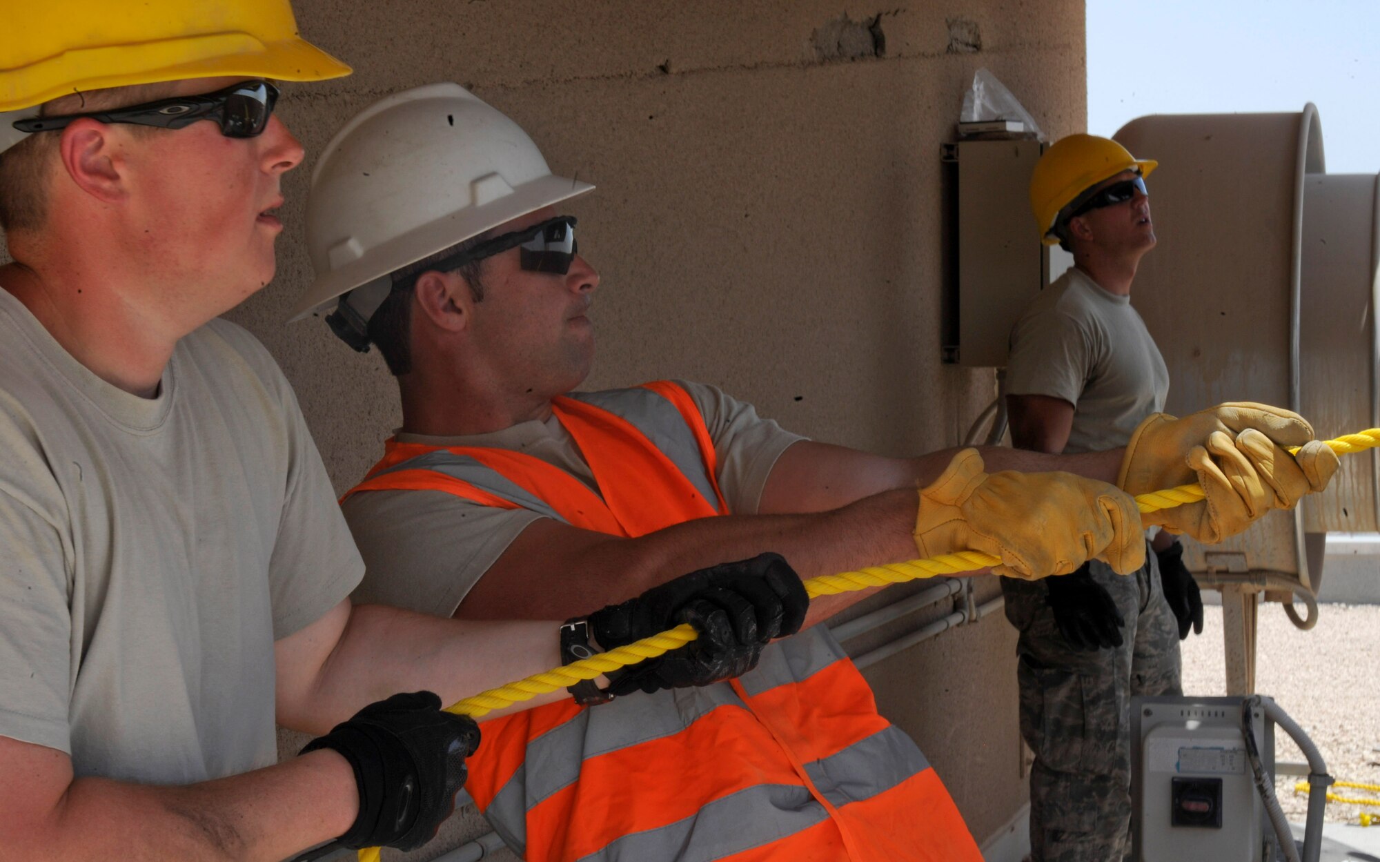 Senior Airman Jordan Cunningham and Staff Sgt. Jordan Weaver pull a rope to position the air conditioning unit being lower onto the rooftop as Airman 1st Class Jarrett Welton serves as a spotter at the 379th Air Expeditionary Wing in Southwest Asia, June 28, 2013. Cunningham is a 379th Expeditionary Civil Engineer Squadron horizontal heavy repair journeyman deployed from Malstrom Air Force Base, Mo.; Weaver is a 379th ECES Heating Vent and Air Conditioning craftsman deployed from Dover Air Force Base, Del.; and Welton is a 379th ECES HVAC journeyman deployed from Kadena Air Base, Japan. (U.S. Air Force photo/Senior Airman Bahja J. Jones) 
