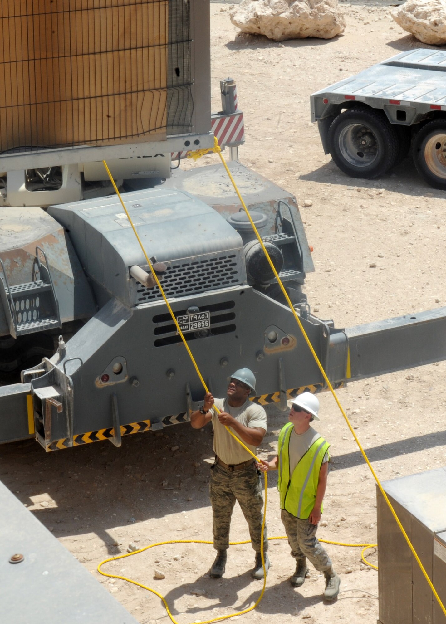 Master Sgt. Edward Jones Jr. and Airman 1st Class Jesse Brandon use a rope to steady an air conditioning unit as it is lifted to the top of a dormitory building at the 379th Air Expeditionary Wing in Southwest Asia, June 28, 2013. Jones is the 379th Expeditionary Civil Engineer Squadron horizontal heavy repair section chief deployed form Ramstein Air Base, Germany and Brandon is a 379th ECES horizontal heavy repair journeyman deployed from Malstrom Air Force Base, Mo. (U.S. Air Force photo/Senior Airman Bahja J. Jones) 