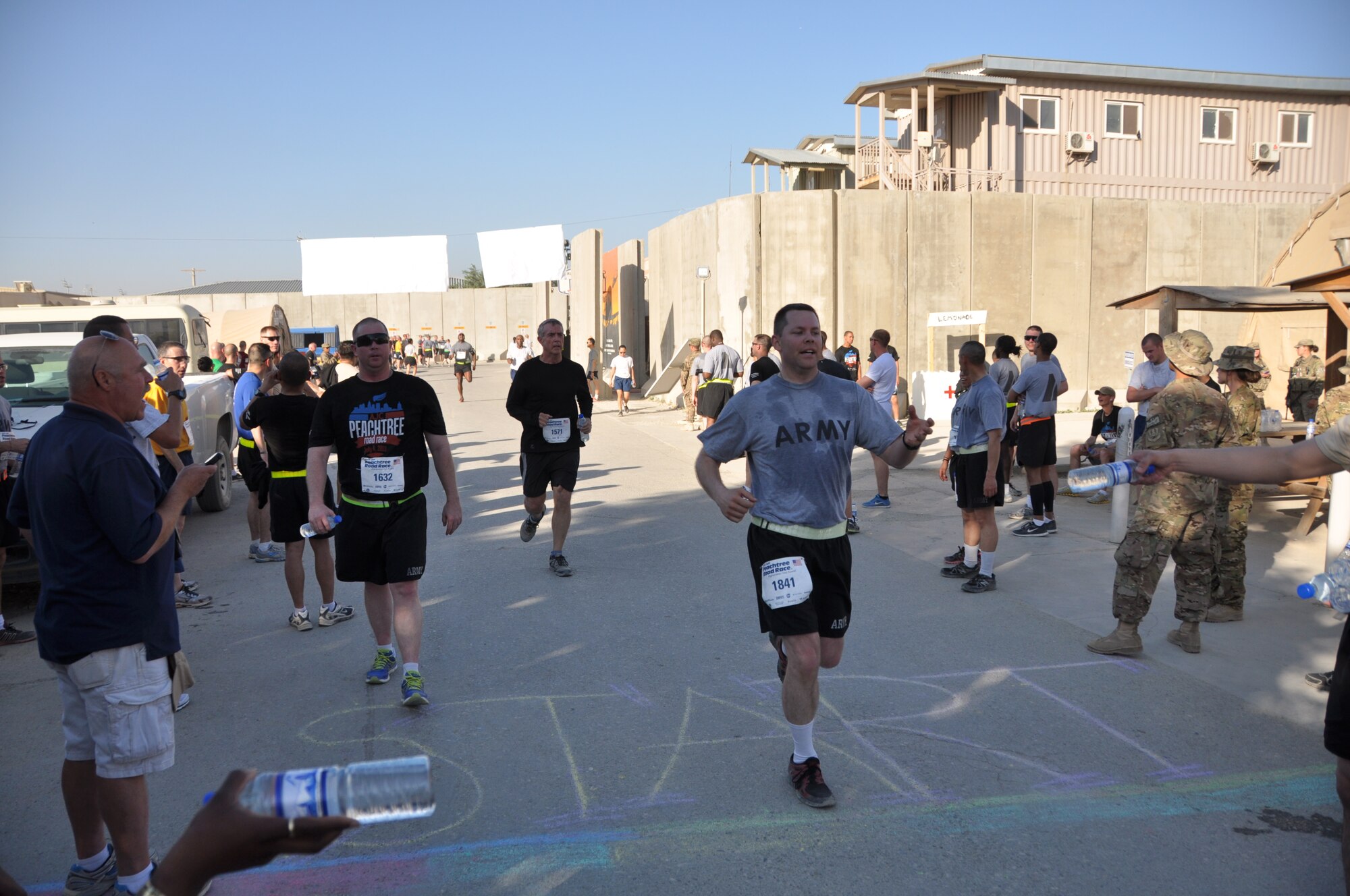 Several runners reach the finish line during an overseas shadow race for the Peachtree 10-kilometer run on Bagram Airfield, Afghanistan, July 4. The morale, welfare and recreation office coordinated with the Atlanta Track Club to hold the road race, which drew more than 600 runners. (U.S. Air Force photo/Tech. Sgt. Rob Hazelett)