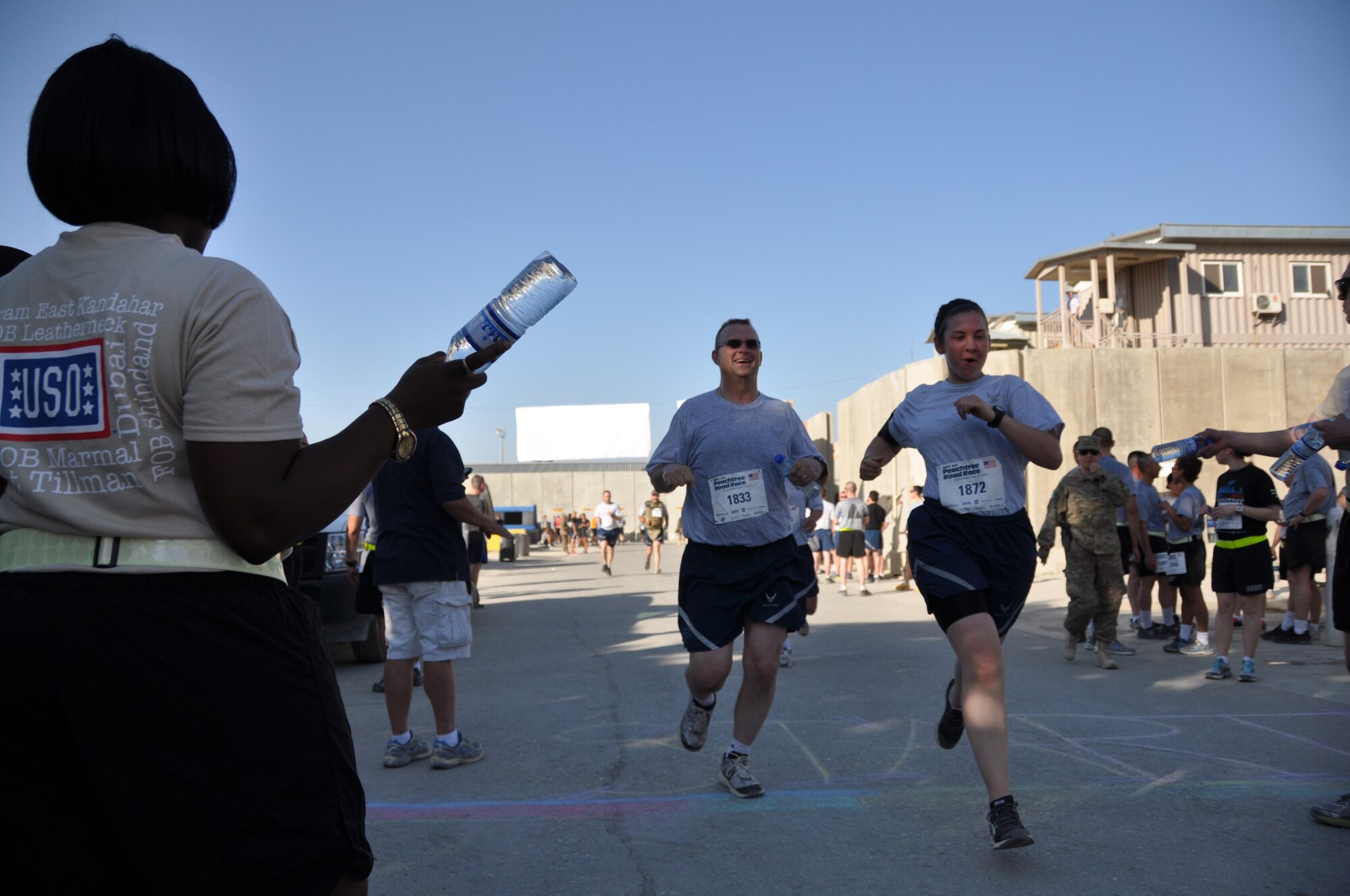 Two runners reach the finish line during an overseas shadow race for the Peachtree 10-kilometer run on Bagram Airfield, Afghanistan, July 4. The morale, welfare and recreation office coordinated with the Atlanta Track Club to hold the road race, which drew more than 600 runners. (U.S. Air Force photo/Tech. Sgt. Rob Hazelett)