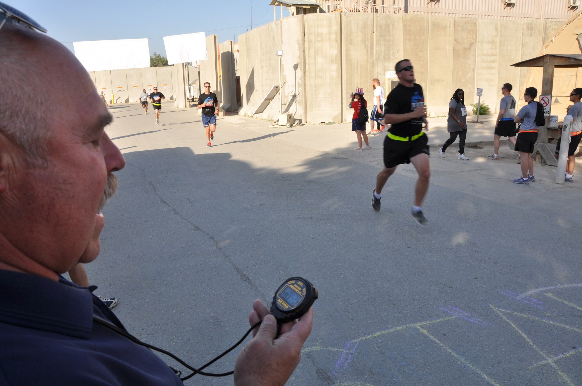 A runner crosses the finish line during an overseas shadow race for the Peachtree 10-kilometer run on Bagram Airfield, Afghanistan, July 4. The morale, welfare and recreation office coordinated with the Atlanta Track Club to hold the road race, which drew more than 600 runners. (U.S. Air Force photo/Tech. Sgt. Rob Hazelett)