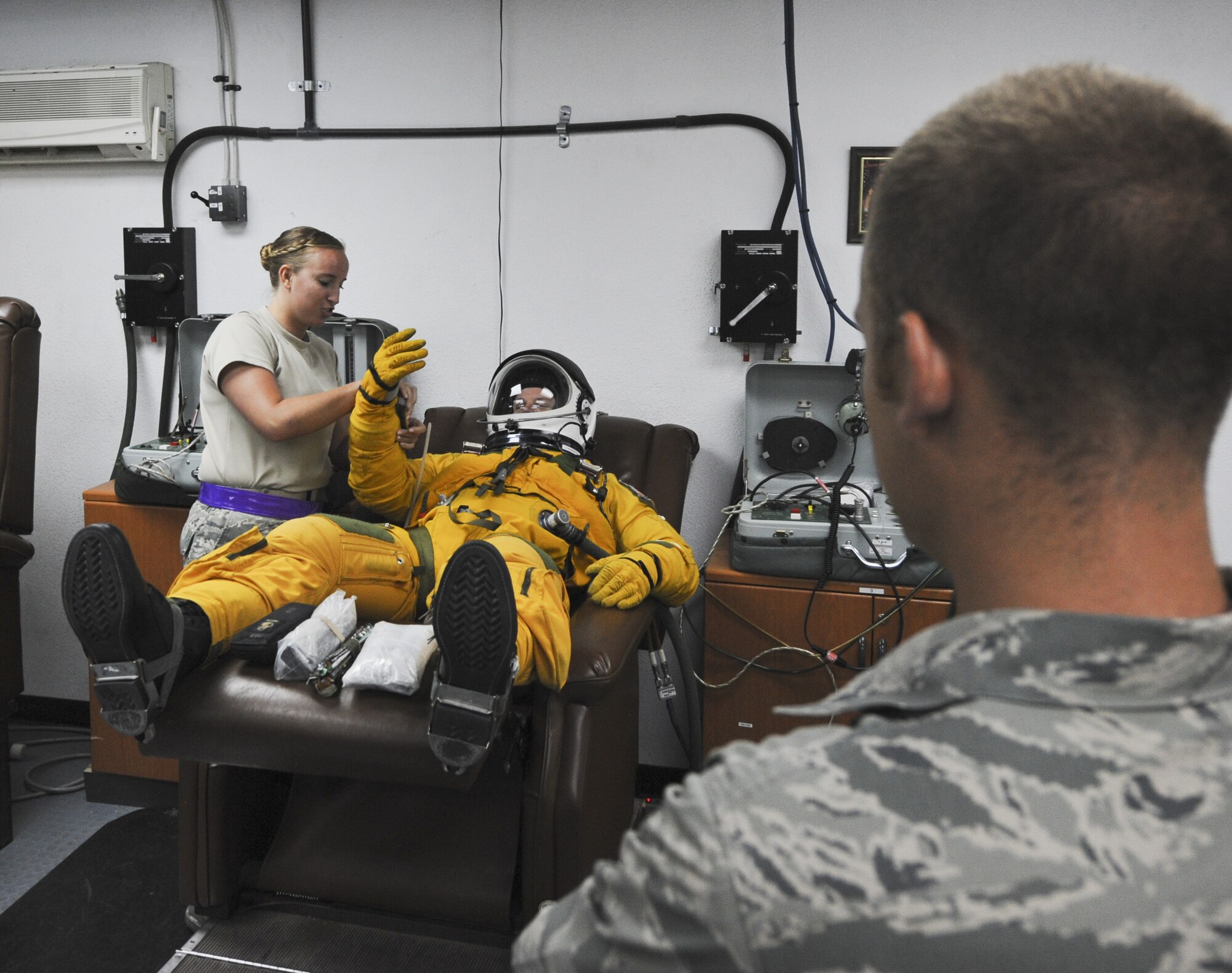 Staff Sgt. Vanessa Jordan, left, 99th Expeditionary Reconnaissance Squadron physiological support supervisor, assists Capt. Gregory Mansfield, 99th ERS U-2 Dragon Lady pilot put his gloves on as Cadet Ryan Holler looks on at an undisclosed location in Southwest Asia June 27, 2013. Holler was visiting the 380th Air Expeditionary Wing as part of the Air Force Academy’s Deployed Operations program. (U.S. Air Force photo by Senior Airman Jacob Morgan)