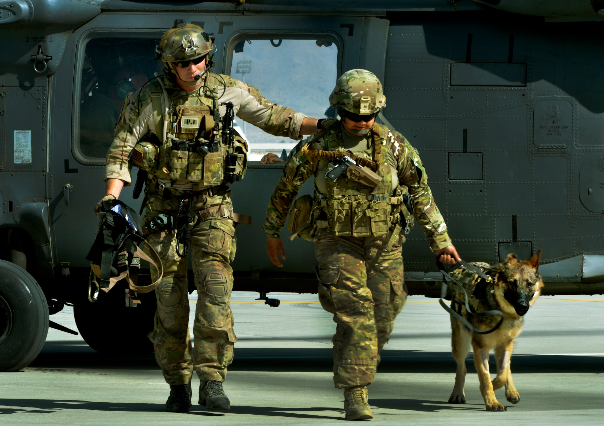 Senior Airman Jason Fischman, 83rd Expeditionary Rescue Squadron pararescueman, U.S. Army Sergeant Nina Alero, tactical explosive detection dog handler and her dog Rex, step off a HH-60G Pave Hawk helicopter during rescue training at Bagram Airfield, Afghanistan, June 21.  This training was a first for both branches and prepared them for future rescue missions. (U.S. Air Force photo/ Staff Sgt. Stephenie Wade) 