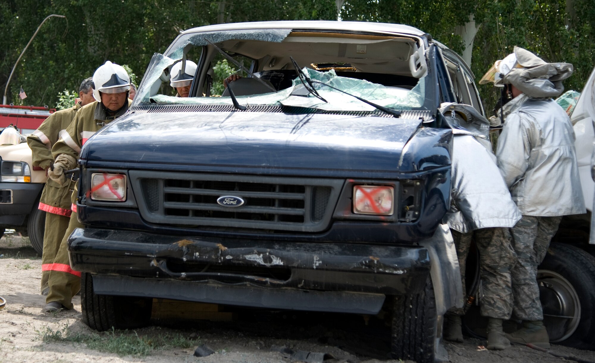 Fire department crews from the Kyrgyz Republic, Manas International Airport and 376th Expeditionary Civil Engineer Squadron, work together to cut through the front of a vehicle during a joint exercise at Transit Center at Manas, Kyrgyzstan, June 27, 2013. The four-day event including four Kyrgyz and two U.S. crews, focused on rapidly saving a trapped victim. (U.S. Air Force photo/Staff Sgt. Krystie Martinez)