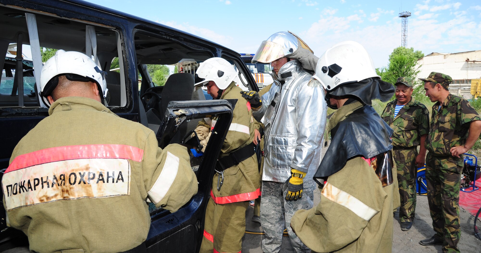 Fire department crews from the Kyrgyz Republic, Manas International Airport and 376th Expeditionary Civil Engineer Squadron, remove the door of a simulated accident vehicle during a joint exchange at Transit Center at Manas, Kyrgyzstan, June 27, 2013. The event focused on the departments sharing vehicle accident passenger rescue methods. (U.S. Air Force photo/Staff Sgt. Krystie Martinez)