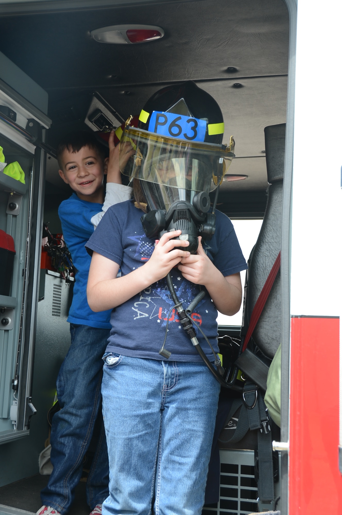 ROYAL AIR FORCE LAKENHEATH, England – Brooklyn McDonald, 11-year-old daughter of Staff Sgt. James McDonald, 48th Equipment Maintenance Squadron air ground equipment, tries on firefighting equipment with the help of her brother Gavin, 7, at the 48th Maintenance Group Fourth of July Fest, July 4, 2013. The 48th MXG hosted food booths, games for kids, and a softball tournament. (U.S. Air Force photo by Airman 1st Class Trevor T. McBride) 