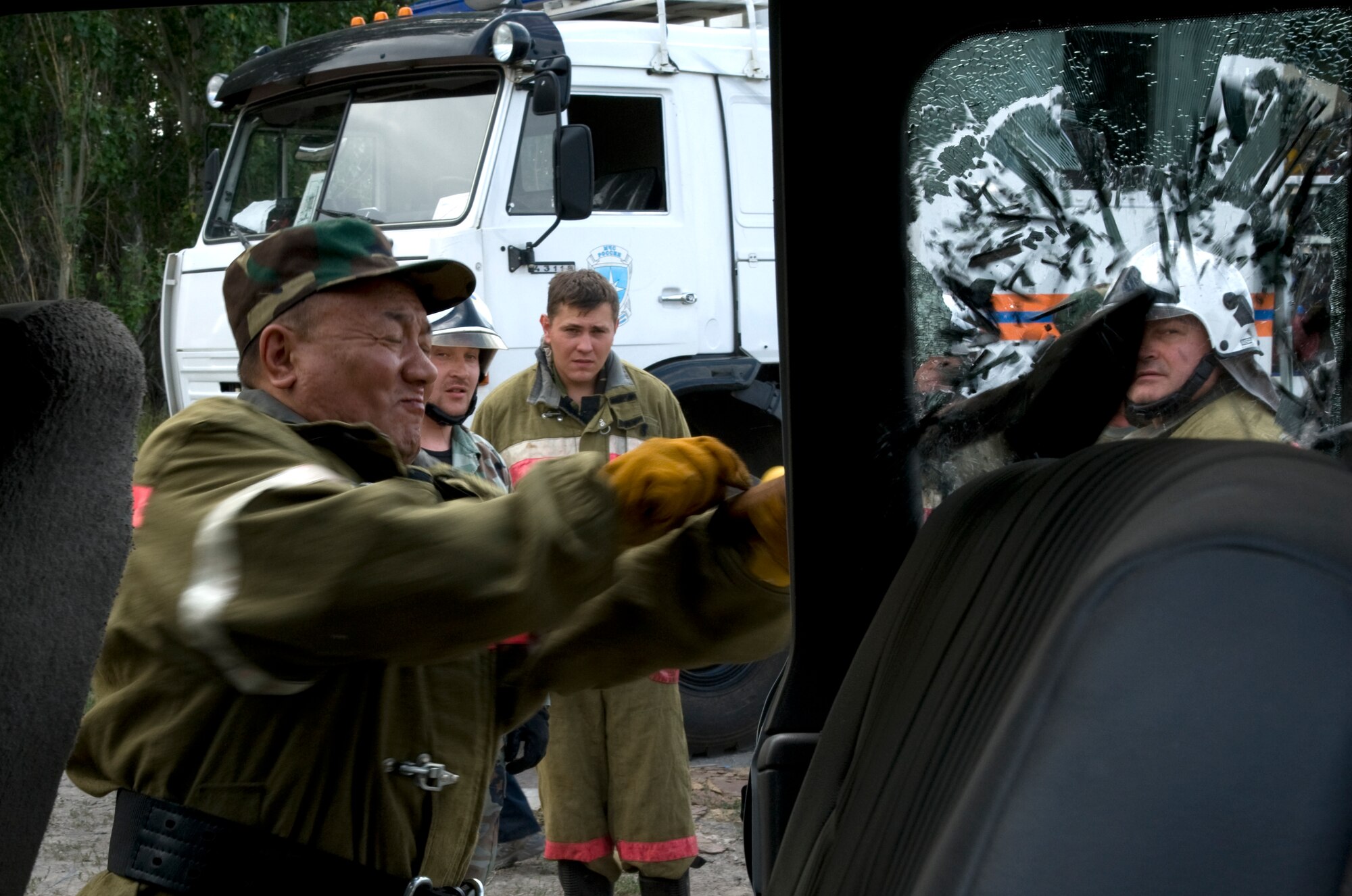 A Kyrgyz Republic, Manas International Airport firefighter shatters a vehicle window during an exercise hosted by the 376th Expeditionary Civil Engineer Squadron fire department at Transit Center at Manas, Kyrgyzstan, June 26, 2013. The joint exercise gave both crews the opportunity to share rescue techniques and build stronger ties with one another. (U.S. Air Force photo/Staff Sgt. Krystie Martinez)