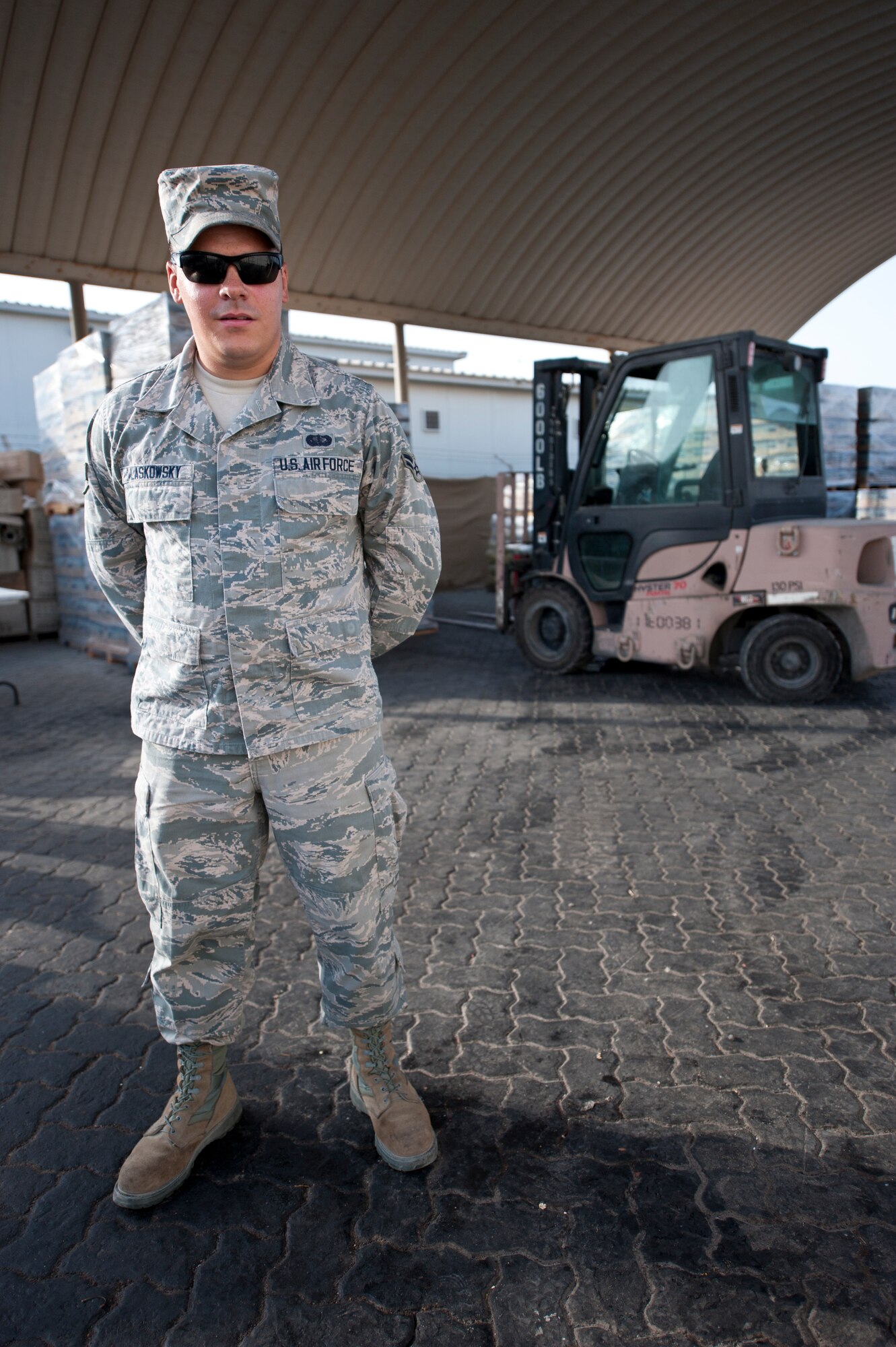 U.S. Air Force Airman 1st Class Mickey Laskowsky, 380th Expeditionary Force Support Squadron food services technician, poses for a photo in front of his 6K loader and a stockpile of water for the base at an undisclosed location in Southwest Asia July 3, 2013. Laskowsky is the main forklift operator for the 380th EFSS where he uses it to deliver water to 58 different stops a day. He is originally from Pittsburgh, Penn., and is stationed with the 171st Air Refueling Wing with the Pennsylvania Air National Guard. (U.S. Air Force photo by Senior Airman Jacob Morgan)