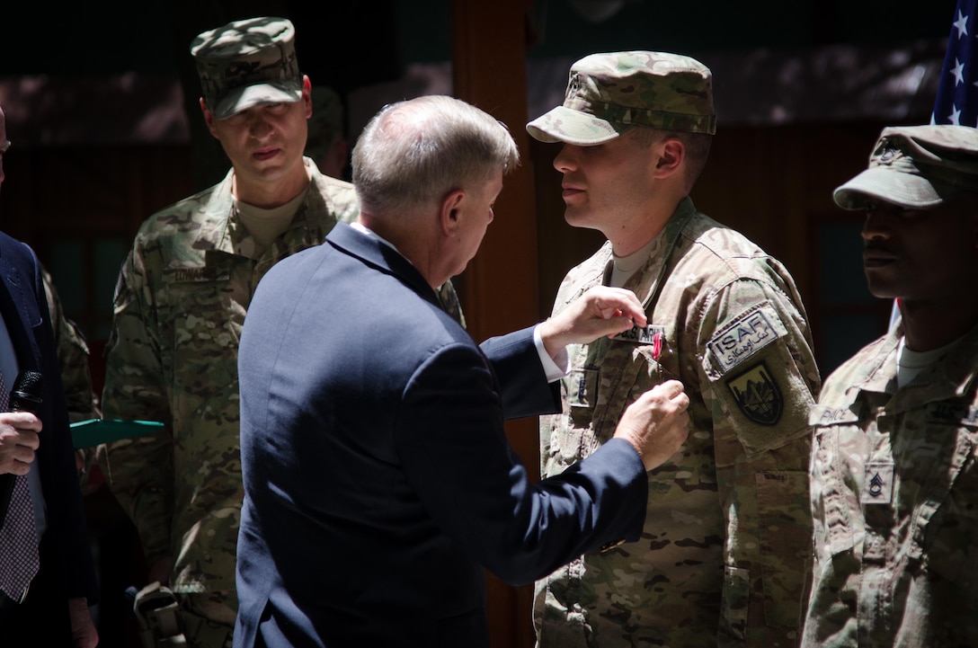 U.S. Sen. Lindsey Graham pins a Bronze Star Medal on 1st Lt. Christopher Michels during an Independence Day celebration at International Security Assistance Force headquarters in Kabul, Afghanistan, July 4, 2013. Graham and U.S. Sen. John McCain promoted, re-enlisted and awarded soldiers during the event.