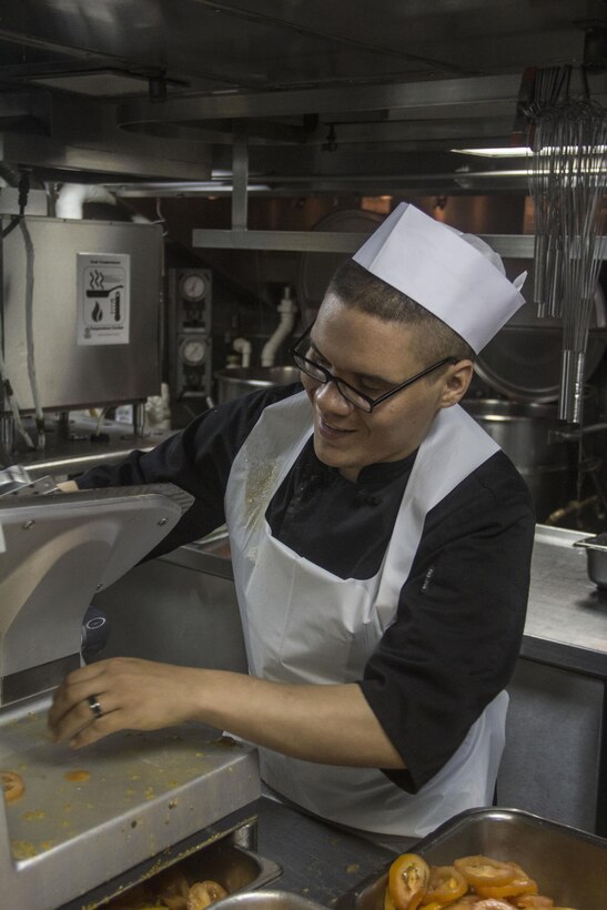 U.S. Marine Corps Sgt. Jonathan Deletorre, food service specialist from Union City, N.J., slices tomatoes aboard the USS Carter Hall (LSD 50) while at sea July 3, 2013. The 26th MEU is a Marine Air-Ground Task Force forward-deployed to the U.S. 5th Fleet area of responsibility aboard the Kearsarge Amphibious Ready Group serving as a sea-based, expeditionary crisis response force capable of conducting amphibious operations across the full range of military operations. (U.S. Marine Corps photo by Cpl. Michael S. Lockett/Released)