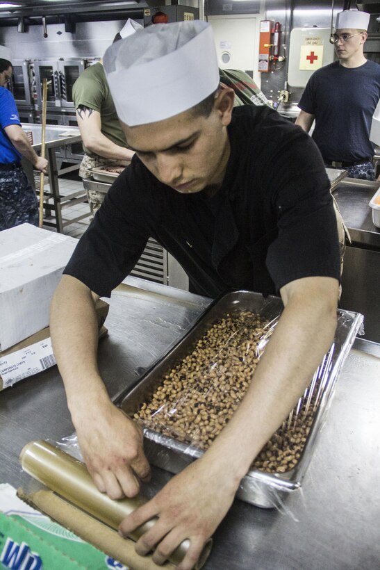 U.S. Marine Corps Lance Cpl. Alejandro Sanchez, food service specialist from Salinas, Calif., wraps a tray of beans aboard the USS Carter Hall (LSD 50) while at sea July 3, 2013. The 26th MEU is a Marine Air-Ground Task Force forward-deployed to the U.S. 5th Fleet area of responsibility aboard the Kearsarge Amphibious Ready Group serving as a sea-based, expeditionary crisis response force capable of conducting amphibious operations across the full range of military operations. (U.S. Marine Corps photo by Cpl. Michael S. Lockett/Released)