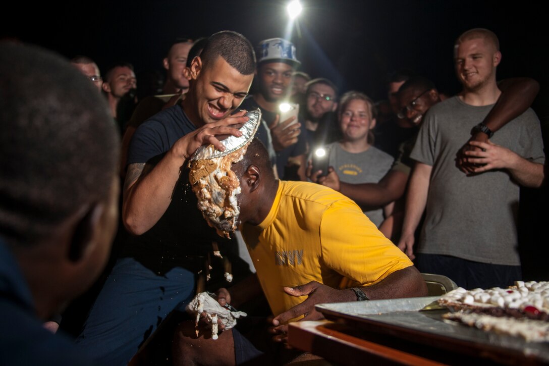 A Sailor aboard the USS Carter Hall (LSD 50) pies U.S. Navy Cmdr. Greg Blyden, USS Carter Hall commanding officer, in front of a crowd of U.S. Marines and Sailors assigned to the 26th Marine Expeditionary Unit (MEU) and the USS Carter Hall during their Independence Day celebration while at sea July 4, 2013. The 26th MEU is a Marine Air-Ground Task Force forward-deployed to the U.S. 5th Fleet area of responsibility aboard the Kearsarge Amphibious Ready Group serving as a sea-based, expeditionary crisis response force capable of conducting amphibious operations across the full range of military operations. (U.S. Marine Corps photo by Staff Sgt. Edward Guevara/Released)