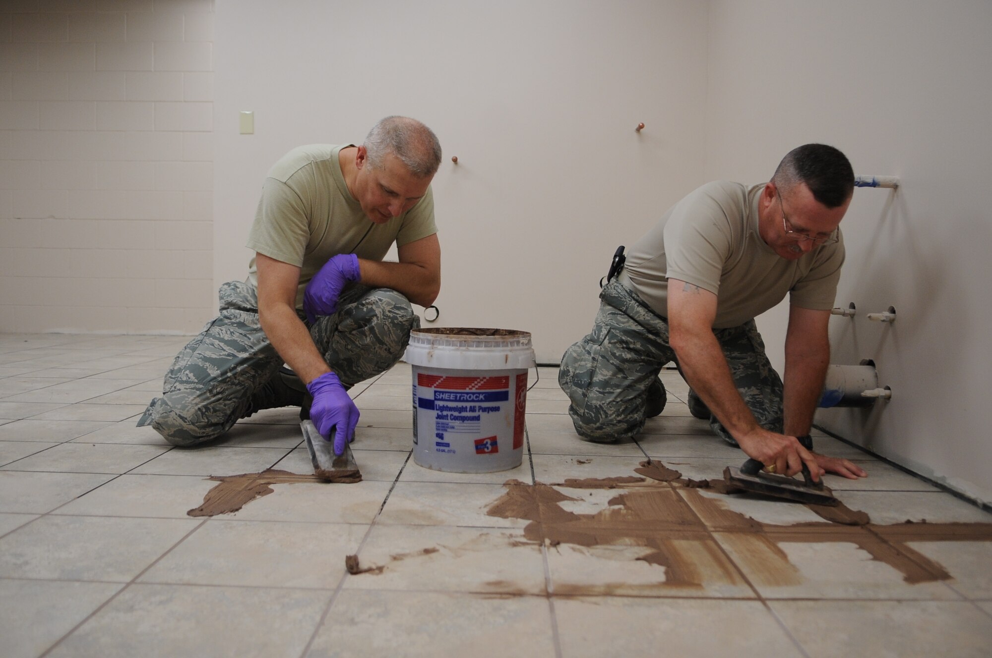 Col. Paul Bauman, 319th Air Base Wing commander, and Chief Master Sergeant David Duncan, 319th ABW command chief, grout tile in a renovation project that the 319th Civil Engineer Squadron is completing in the 319th Logistics Readiness Squadron headquarters building on Grand Forks Air Force Base, N.D., June 20, 2013. Bauman and Duncan are getting their hands dirty working day-to-day jobs with the Wing’s Airmen. (U.S. Air Force photo/Staff Sgt. Amanda Grabiec) 