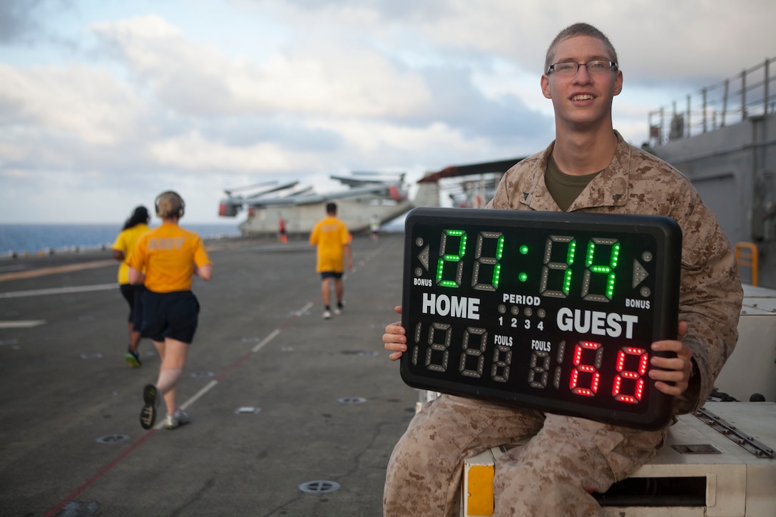 Lance Cpl. Gregg J. Schefer, a landing support specialist with Combat Logistics Battalion 31, 31st Marine Expeditionary Unit, and a native of St. Louis, Mo., holds the timer for a 5 kilometer Fun Run here, July 7. The Navy and Marine participants ran laps around the flight deck to reach their goal of 1.5 or 3 miles in the fastest time. Once all of the runners were finished, the fastest members of each category, determined by age and gender, were given medals. The 31st MEU is the only continuously deployed MEU and is the Marine Corps’ force in readiness in the Asia-Pacific region. 