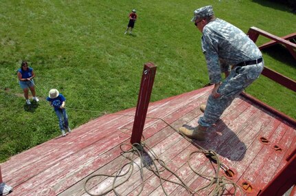 A Soldier watches a member of Blue Platoon conquer a rappel tower during the Indiana National Guard Youth Camp at Camp Atterbury, Ind. The camp is designed to give military children a chance to spend a week in their parent's shoes while learning about the importance of team-building and peer support.