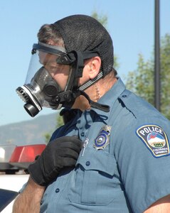 COLORADO SPRINGS, Colo. - Colorado Springs Police Department Officer J. W. Reutner dons a gas mask following a simulated chemical attack during the Coalition Warrior Interoperablity Demonstration June 16. The exercise, simulating a bomb and chemical attack in Colorado Springs, brought together members of U.S. Northern Command, the city of Colorado Springs and the University of Colorado at Colorado Springs first responders to respond to the exercise while simultaneously testing new technologies to make communicating between the groups more efficient. (U.S. Air Force photo by Staff Sgt. Thomas J. Doscher)