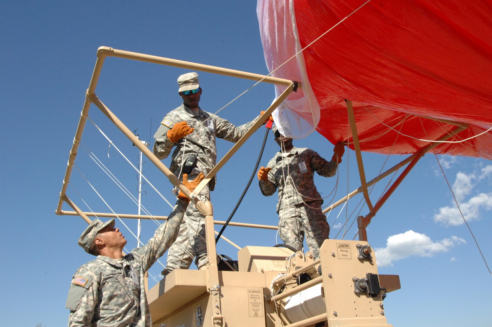 COLORADO SPRINGS, Colo. - Army Pvt. Sherman Huff, 207th Army Liaison Team, helps Army Pfc. Aaron Garlington, 206th Army Liaison Team, and Spc. Shaun Marshall, 207th ALT, inflate a helium-filled aerostat surveillance balloon during the Coalition Warrior Interoperablity Demonstration June 16. The goal of the demonstration was to have military members use and assess new technologies in operational conditions. Equipment tested included aerostat balloons and hand-held phones that could switch between cellular and satellite with the push of a button. (U.S. Air Force photo by Staff Sgt. Thomas J. Doscher)