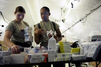 From left, U.S. Air Force Airman 1st Class Vanessa Alaquinez and 1st Lt. Nicole Ferguson, both with the 59th Pharmacy Squadron out of Lackland Air Force Base, Texas, gather pharmaceutical supplies in the Expeditionary Medical System during exercise Vibrant Response July 14, 2010, at Camp Atterbury, Ind. Vibrant Response 10.2 Field Training Exercise was a U.S. Army North training event for the chemical, biological, radiological, nuclear, high yield explosives consequence management response force 10.2. (U.S. Air Force photo by Airman 1st Class Samuel W. Goodman/Released)