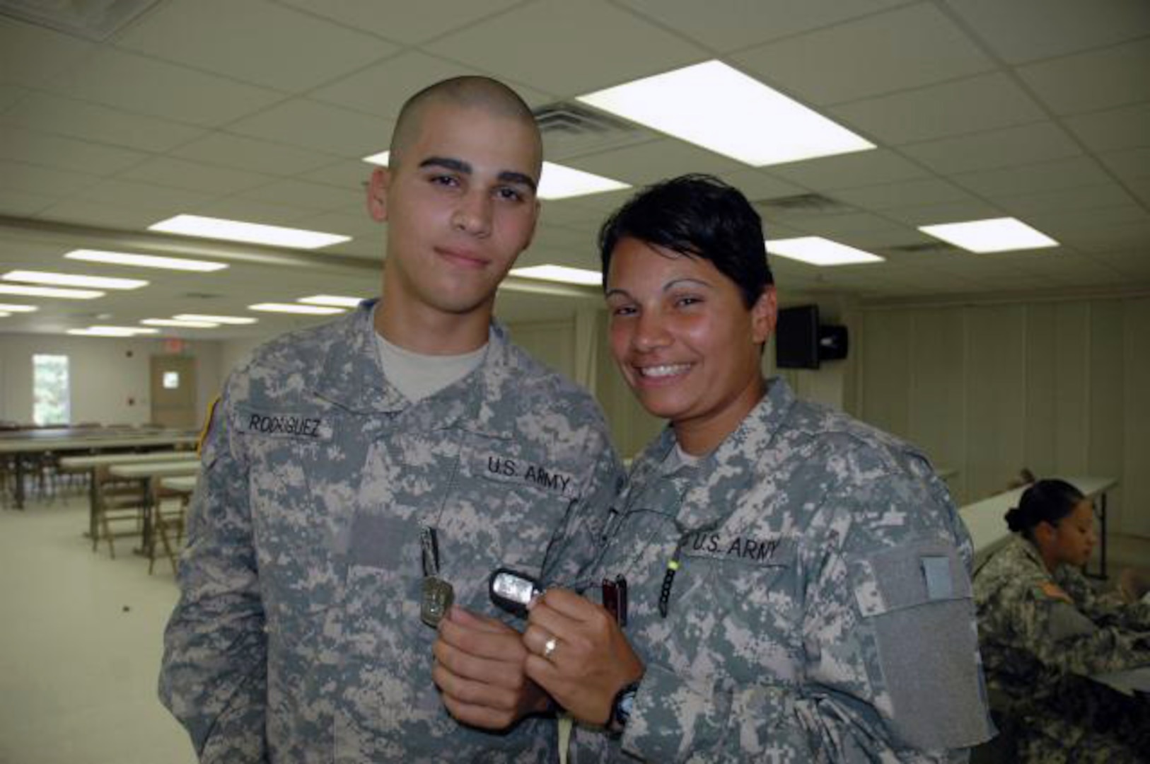 Pvt. Carmen Egipciaco, Company F, 1st, Battalion, 13th Infantry Regiment, and her son Pvt. David Rodriguez, Company C, 2nd Battalion, 60th Infantry Regiment, exchange identification tags as a symbol of their bond and their support of each other during Basic Combat Training.