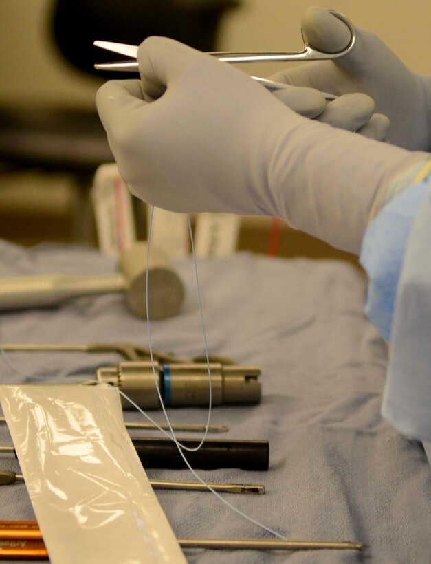 A surgical technician cuts suturing line during a shoulder surgery, June 26, at Fort Eustis, Va. The new operating room in McDonald Army Health Center provides more room for surgeons and staff to move around, giving them space to perform delicate surgeries. (U.S. Air Force photo by Airman 1st Class Austin Harvill/Released)