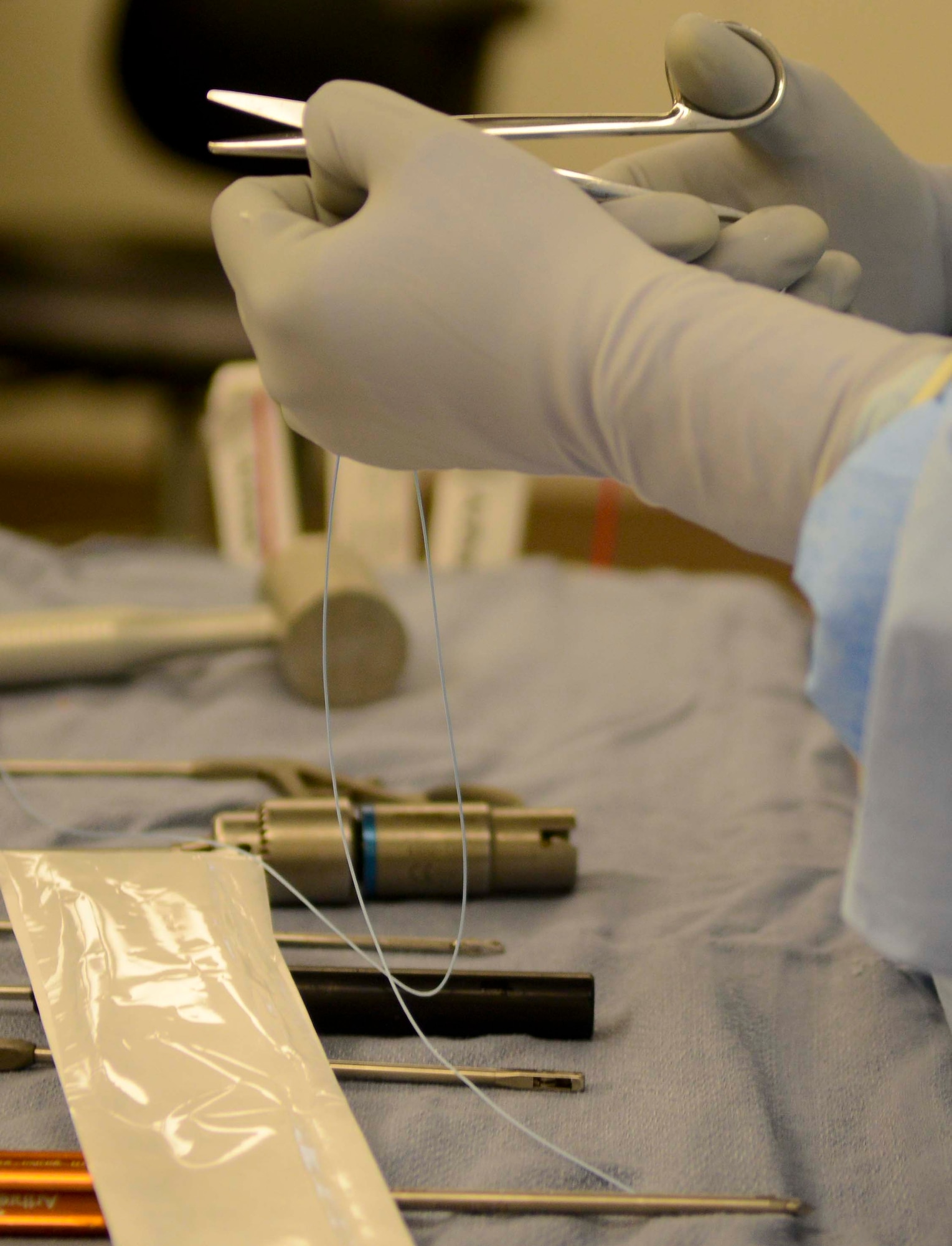 A surgical technician cuts suturing line during a shoulder surgery, June 26, at Fort Eustis, Va. The new operating room in McDonald Army Health Center provides more room for surgeons and staff to move around, giving them space to perform delicate surgeries. (U.S. Air Force photo by Airman 1st Class Austin Harvill/Released)