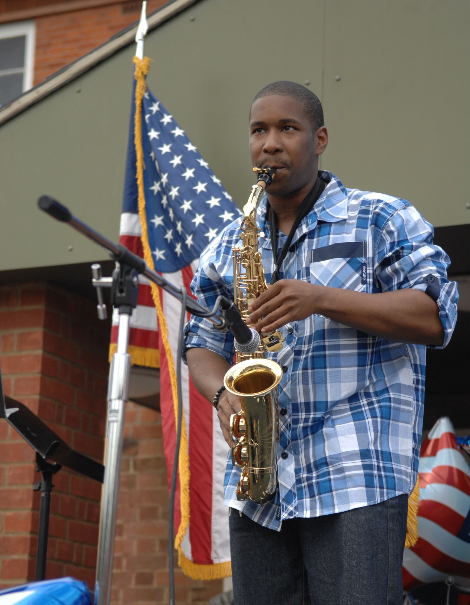 Airman 1st Class Bobby Lucas, 100th Civil Engineer Squadron Fire Department firefighter, plays the saxophone July 3, 2013, during the Independence Day celebration on RAF Mildenhall, England. Lucas, along with other musical and spoken-word acts, performed in Washington Square to celebrate the day the U.S. declared its independence. (U.S. Air Force photo by Airman 1st Class Dillon Johnston/Released)
