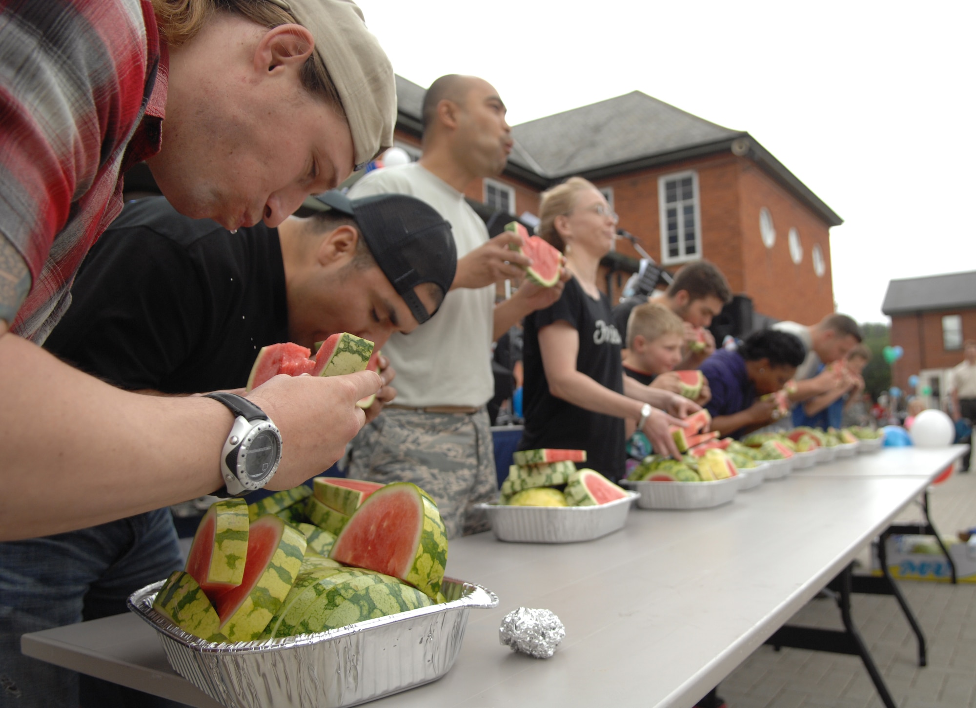 Team Mildenhall members participate in a watermelon eating contest July 3, 2013, during the Independence Day celebration on RAF Mildenhall, England. Contestants had to eat as much watermelon in the time given; the winner received a gift card as a prize. The celebration, similar to an American county fair, was designed to make Airmen feel more at home, even while overseas. (U.S. Air Force photo by Airman 1st Class Dillon Johnston/Released)