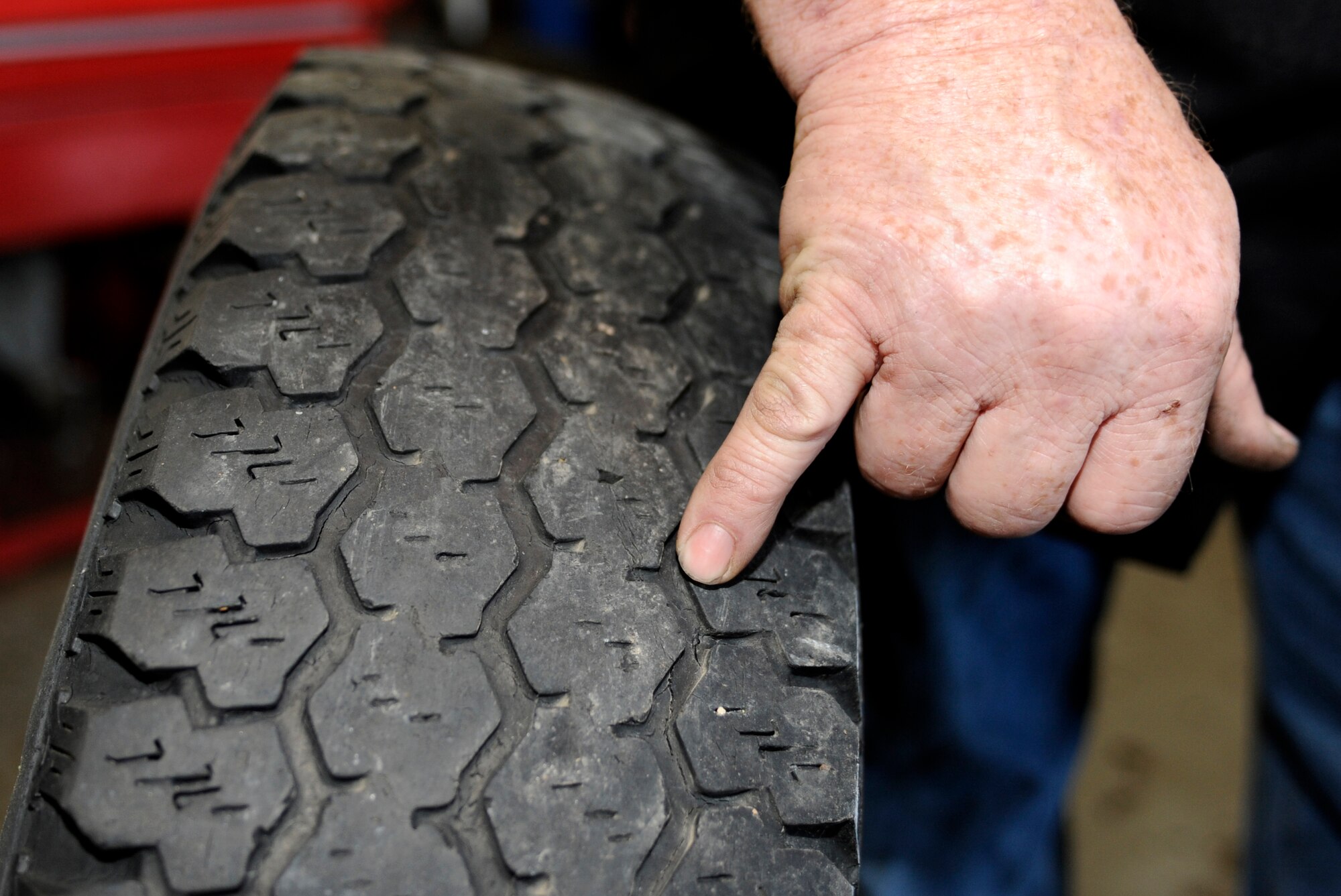 Dave Roney, 28th Force Support Squadron Auto Hobby Center manager, points out cracks in a tire in the Auto Hobby Center at Ellsworth Air Force Base, S.D., July 2, 2013. The condition of vehicle tires should be monitored since summer temperatures can put added stress on any weak spots and can cause a blowout. (U.S. Air Force photo by Airman 1st Class Ashley J. Thum/Released)