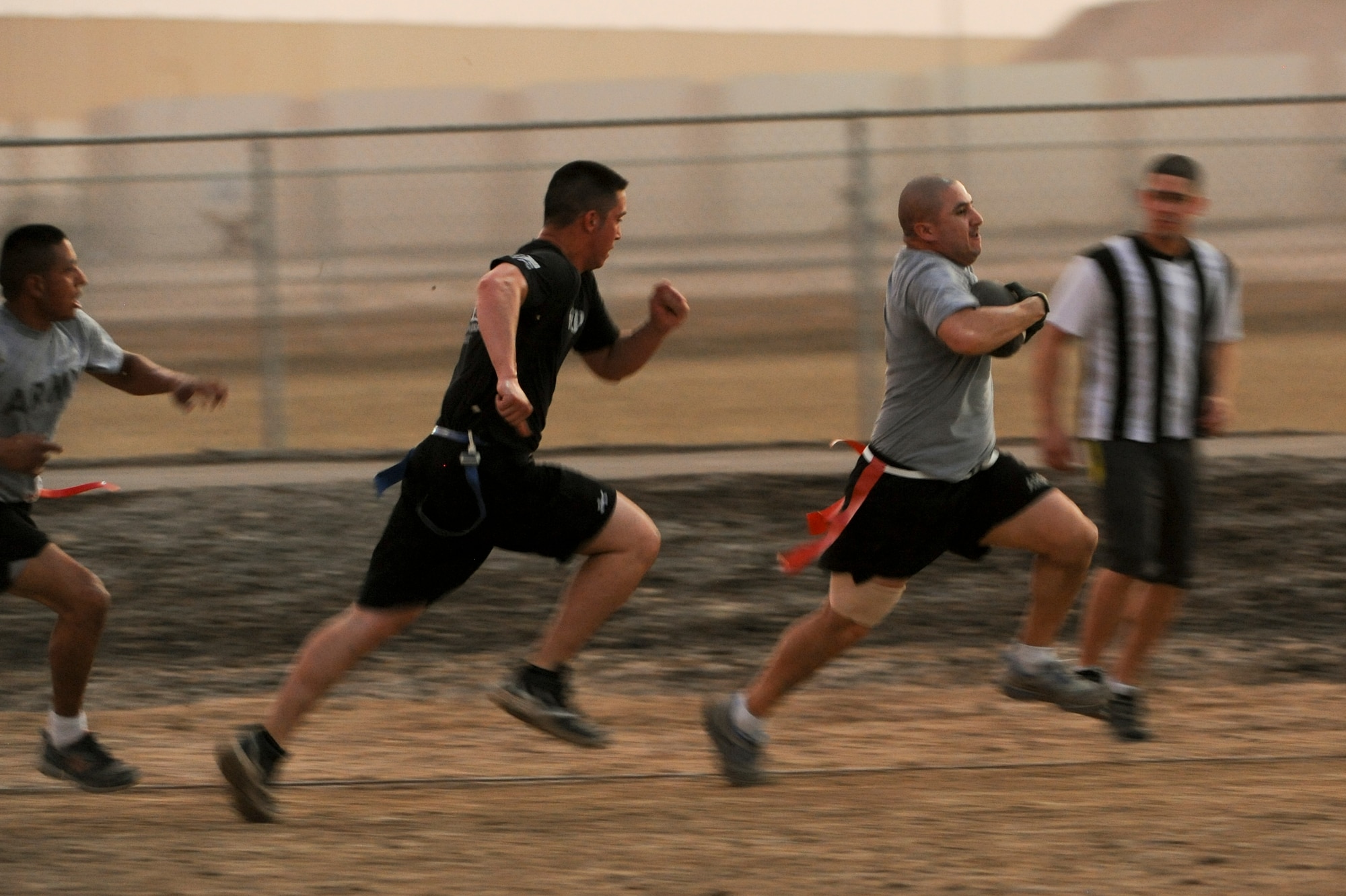 Cesar Guerra, running back for the 1-62 Air Defense Artillery Battalion flag football team runs past defenders during the Air Force vs. Army football at an undisclosed location in Southwest Asia July 4, 2013. The game kicked off an event filled weekend celebrating Independence day. Guerra is deployed from Ft. Hood, Texas. (U.S. Air Force photo by Staff Sgt. Joshua J. Garcia)
  