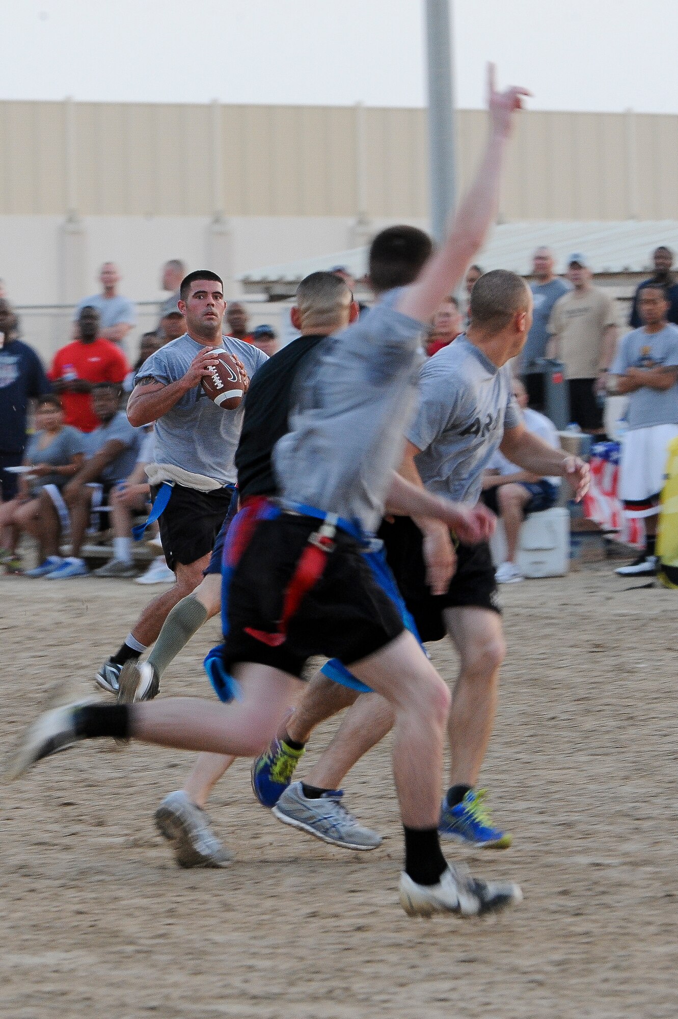 Thomas Adair, quarterback for the 1-62 Air Defense Artillery Battalion flag football team, looks for a receiver during the Army vs. Air Force game at an undisclosed location in Southwest Asia, Jul 4, 2013. The game kicked off several events that the 380th Air Expeditionary Wing hosted for the Independence Day holiday weekend. Army went on to win the game 25-19. Adair is deployed from Ft. Hood, Texas. (U.S. Air Force photo by Staff Sgt. Joshua J. Garcia)  