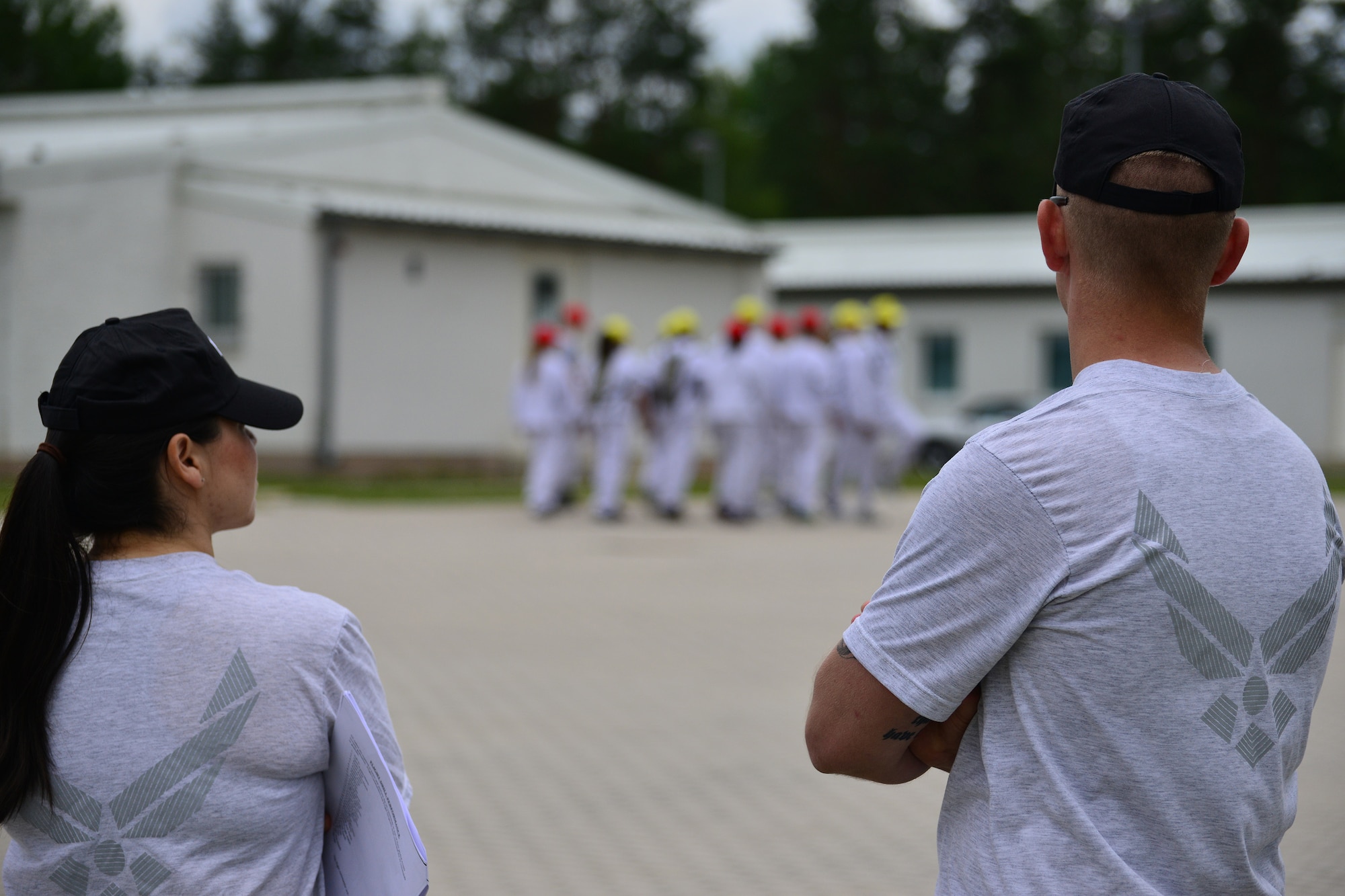 Tech. Sgt. Christian Johnson, 603rd Air and Space Operations Center, and Staff Sgt. Cody Crunelle, 569th U.S. Forces Police Squadron, watch a group of Air Force Junior Reserve Officers’ Training Corps cadets march June 24, 2013, Grafenwoehr, Germany. Sixty-six high school students from around Europe attended the Air Force Junior Reserve Officers’ Training Corps summer program June 23-29. (U.S. Air Force photo/Tech. Sgt. Chad Thompson)